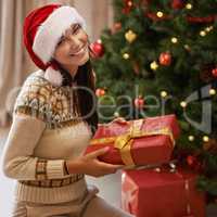 Putting the presents under the tree. Portrait of an attractive young woman putting presents under the Christmas tree.