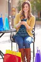 I found some awesome bargains today. Shot of an attractive young woman texting a friend about all the bargains she found.