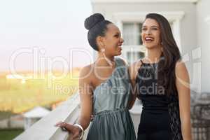 Excitement before the prom. Two young women in evening wear standing on a balcony.