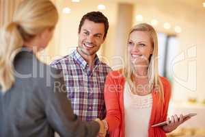 Financial advice you can trust. A happy couple shaking hands with their financial consultant in their home.