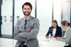 Hes leading the way forward. Portrait of a businessman standing in a boardroom meeting with colleagues in the background.