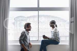Sparks fly when theyre together. A happy young couple laughing and chatting next to a large window.