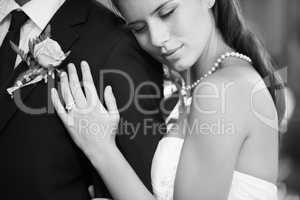 Dreaming in black and white. Black and white image of a beautiful bride embracing her husband from behind lovingly.