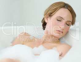 Blissful moments - Beauty. A beautiful young woman closing her eyes and enjoying a luxurious bath.