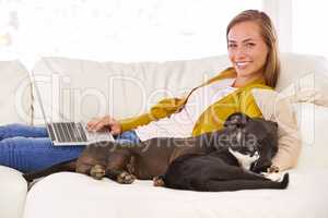 Chilling with my laptop and loyal friend. Portrait of an attractive young woman using a laptop while sitting on the sofa with her dog and cat.