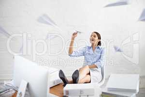 One can only take so much.... Shot of a young businesswoman throwing paper planes while sitting at her desk.