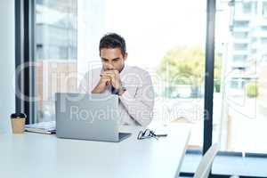 Focus and discipline have always been critical to success. Cropped shot of a businessman sitting with his laptop in his office.