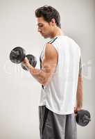Getting in shape one rep at a time. A handsome young man training with dumbbells.