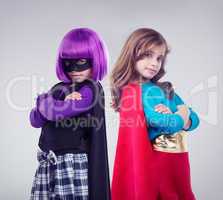 Not every girl wants to be a little princess. A studio shot of two little girls dressed up as a superhero and a villain.