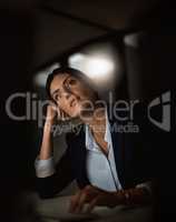 Can it still be considered daydreaming if its at night. Shot of a young businesswoman looking thoughtful during a late night in a modern office.