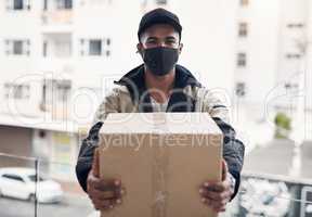 Committed to providing with a safe delivery service. Shot of a masked young man delivering a package to a place of residence.