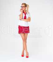 Playful in pigtails. Studio shot of a beautiful young woman in a school uniform against a gray background.