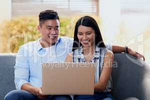 Unwinding in the new age. Shot of a happy young couple using a laptop together on the sofa at home.
