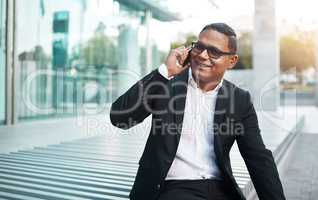 Hes constantly connected. Cropped shot of a handsome mature businessman making a phonecall with his office in the background.