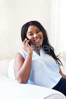 Well hello there, how are you doing today. Shot of a cheerful young woman talking on her cellphone while being seated on a couch at home during the day.