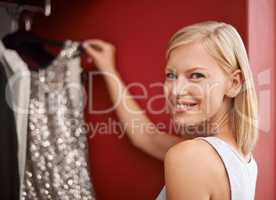 The perfect dress. Portrait of an attractive young woman picking out a dress from her wardrobe.