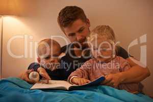 Whats that, Daddy. A father reading a bedtime story to his kids.