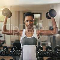 Owning this workout. Shot of a young woman working out with dumbbells at the gym.