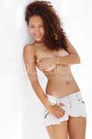 Shes a beautiful sight to behold. Portrait of a topless young ethnic woman wearing jeans and leaning against a wall.