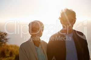 Enjoying a sunset. Cropped view of a senior couple standing on a hillside together.