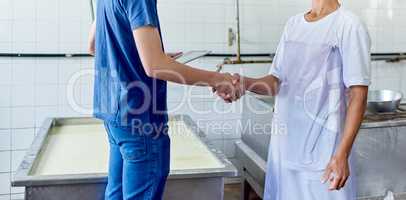 Im glad to be a part of this. Cropped shot of two people shaking hands in a cheese factory.