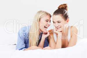 Friendship and laughter. Two best friends sharing a laugh while relaxing in bed.