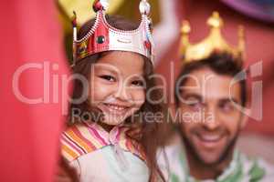 Having so much fun. A cute little girl dressed up as a princess while playing at home with her dad.