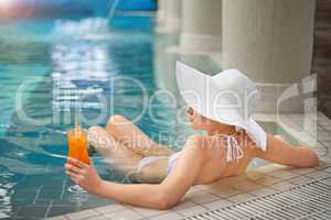 Unplug, unwind and relax. Shot of a young woman relaxing with a cocktail in the pool at a spa.