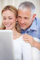 E-mailing family abroad. A young married couple working on their laptop at home.