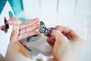 The right tools for crafting. Cropped shot of a womans hands holding a punched out paper butterfly.