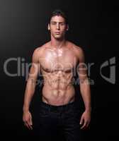I make muscles not excuses. Studio shot of a handsome bare-chested young athlete standing against a black background.