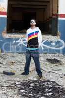 The urban life. A trendy male standing in front of a graffiti wall in a junkyard.