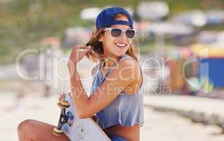 Nothing better than beaching and boarding. Shot of a young woman at the beach with her skateboard.