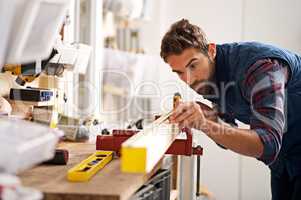 Down to the very last detail. Shot of a handsome young carpenter measuring a piece of wood.