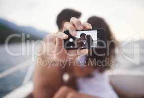 Preserving our holiday memories. Shot of an affectionate young couple taking a self portrait while enjoying a boat ride.