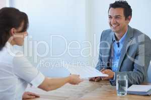 Handing him her resume. A pretty young woman handing her resume to a prospective employer at a job interview.