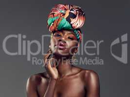 Embrace your culture and look good doing it. Studio shot of a beautiful young woman wearing a traditional African head wrap against a grey background.