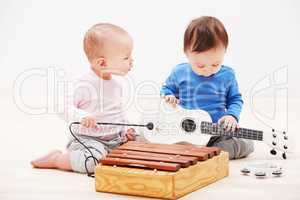 They have the makings of a successful band. Shot of two adorable babies playing with toy musical instruments.