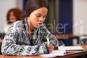 Nothing replaces hard work and diligent focus. Cropped shot of a student working diligently at her desk in class.