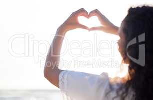 Who doesnt love summer. Shot of an unrecognizable person making a heart gesture with their hands at the beach.