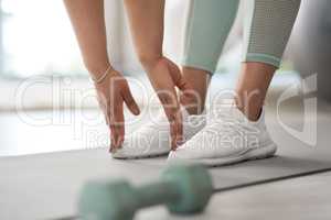 Bend down and touch your feet. Closeup shot of an unrecognisable woman stretching to touch her toes while exercising at home.
