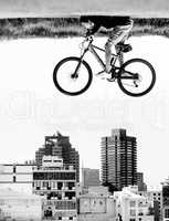 The sky is the limit. A man on a bicycle hovers in the air over the rooftops of a city - perception.