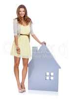 Shes the best realtor around. Full-length portrait of a confident young woman standing beside a prop of a house.