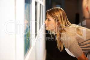 Taking in a century of art. Shot of a young woman looking at paintings in a gallery.