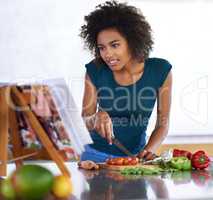 Am I doing this correctly. A young woman cooking from a recipe book.