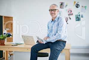 Portrait of a handsome businessman working on a digital tablet. The commercial designs displayed in this image represent a simulation of a real product and have been changed or altered enough by our team of retouching and design specialists so that they a