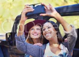 Capturing precious moments between friends. Shot of a two girlfriends taking self-portraits while on a roadtrip.