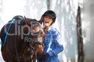 The joys of owning a horse. A beautiful woman laughing outside while standing outside with her horse.