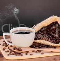 Coffee adds that little oomph to every day. Shot of coffee beans and a cup of black coffee on a wooden table.