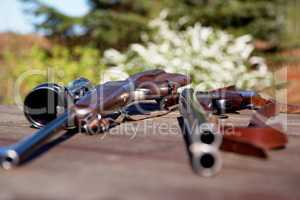 The weapons of choice for an expert hunter. Shot of two guns lying on a table outside.